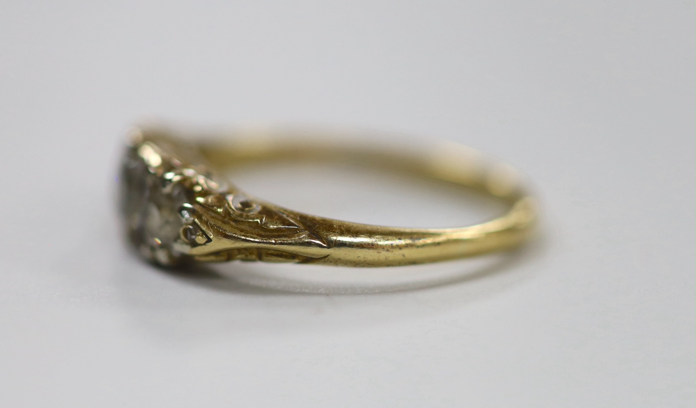 An antique yellow metal and graduated three stone diamond set ring, with diamond chip set spacers, size N/O, gross weight 4 grams